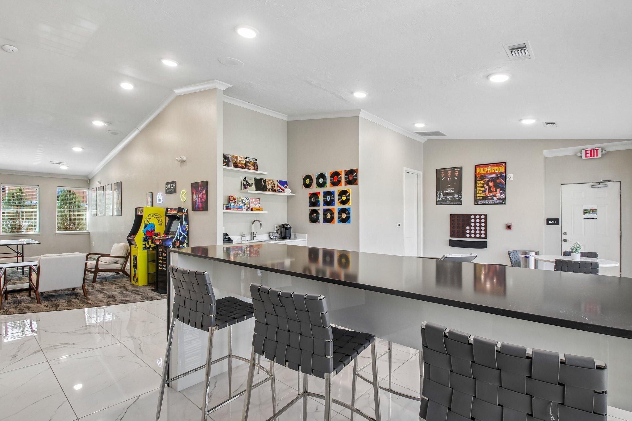 A modern kitchen with a long counter and chairs.